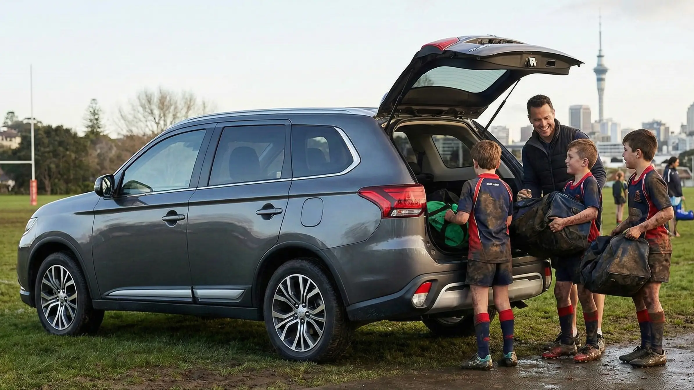 Mitsubishi Outlander 7-seater SUV at rugby field with kids loading muddy sports gear showing family practicality